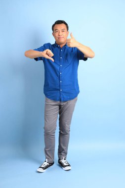 Mavi arka planda duran Asyalı orta yaşlı adam..