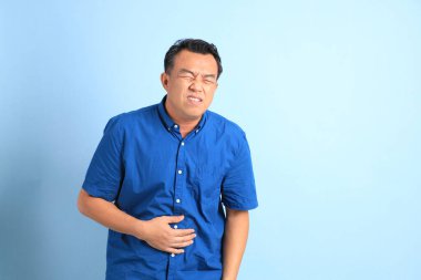 Mavi arka planda duran Asyalı orta yaşlı adam..