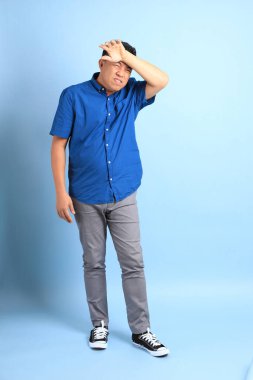 Mavi arka planda duran Asyalı orta yaşlı adam..