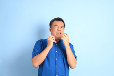 Mavi arka planda duran Asyalı orta yaşlı adam..