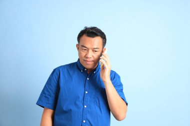 Mavi arka planda duran Asyalı orta yaşlı adam..