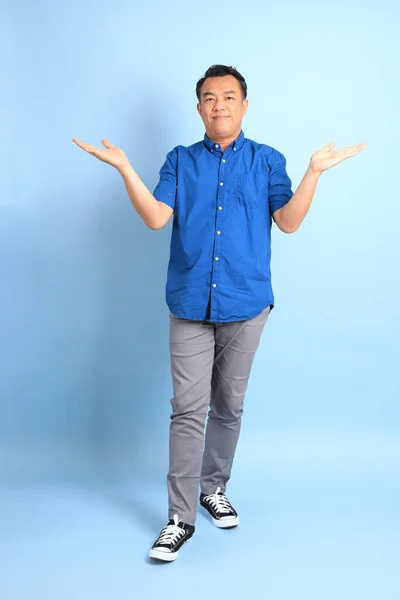 青の背景に青いシャツを着たアジア系の中年男性 — ストック写真