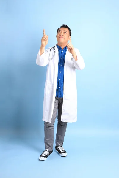 The senior Asian physician standing on the blue background.