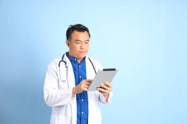 Mavi arka planda duran kıdemli Asyalı doktor..