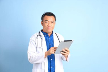 Mavi arka planda duran kıdemli Asyalı doktor..