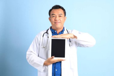 Mavi arka planda duran kıdemli Asyalı doktor..