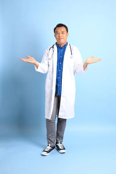 站在蓝色背景上的资深亚洲医生 — 图库照片