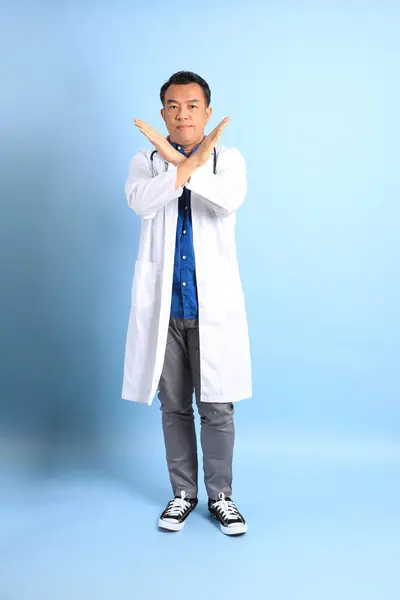 青の背景に立つアジア系の先輩医師 — ストック写真