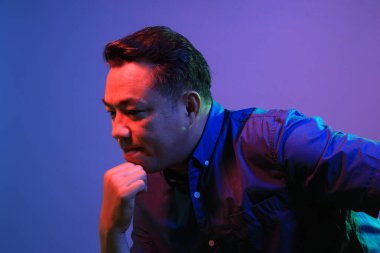 Renkli jel ışıklandırmasının altında mavi arka plandaki havalı kıdemli Asyalı adam.. 