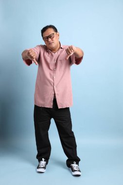 The adult Asian man with pink shirt standing on the blue background.