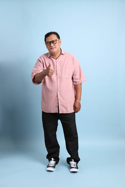 The adult Asian man with pink shirt standing on the blue background.