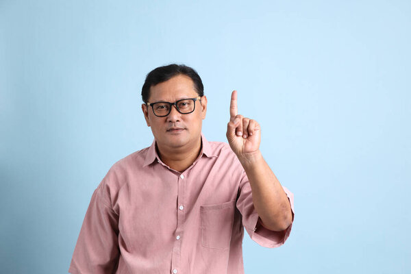 The adult Asian man with pink shirt standing on the blue background.