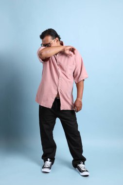 The adult Asian man with pink shirt standing on the blue background.