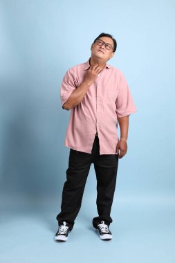 The adult Asian man with pink shirt standing on the blue background.