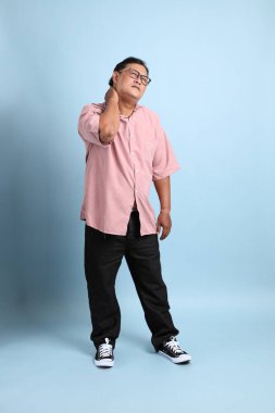 The adult Asian man with pink shirt standing on the blue background.