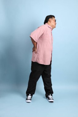 The adult Asian man with pink shirt standing on the blue background.
