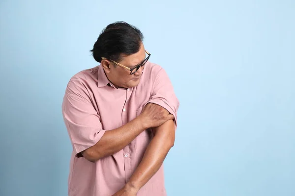 The adult Asian man with pink shirt standing on the blue background.