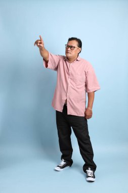 The adult Asian man with pink shirt standing on the blue background.