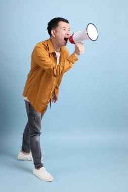 Mavi arka planda duran sarı gömlekli Asyalı LGBTQ adamı..