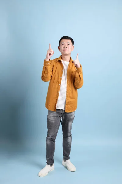 The Asian LGBTQ man with yellow shirt standing on the blue background.