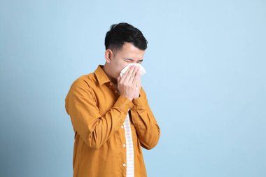 The Asian LGBTQ man with yellow shirt standing on the blue background.