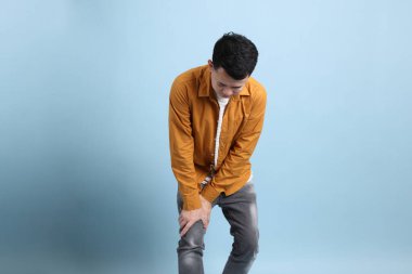 Mavi arka planda duran sarı gömlekli Asyalı LGBTQ adamı..