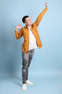 Mavi arka planda duran sarı gömlekli Asyalı LGBTQ adamı..