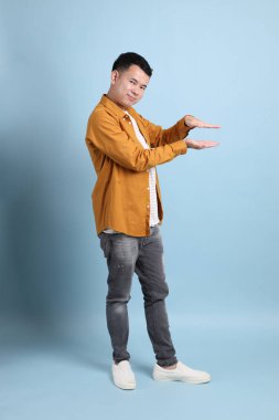 Mavi arka planda duran sarı gömlekli Asyalı LGBTQ adamı..