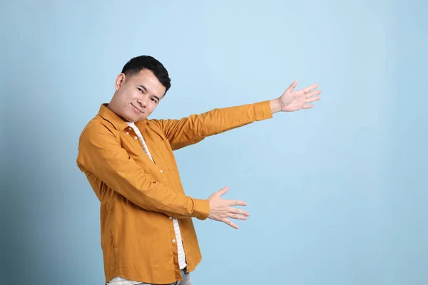 The Asian LGBTQ man with yellow shirt standing on the blue background.