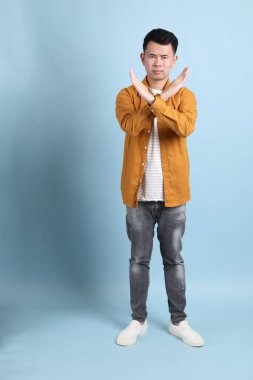 Mavi arka planda duran sarı gömlekli Asyalı LGBTQ adamı..