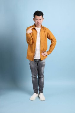 Mavi arka planda duran sarı gömlekli Asyalı LGBTQ adamı..