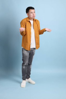 Mavi arka planda duran sarı gömlekli Asyalı LGBTQ adamı..