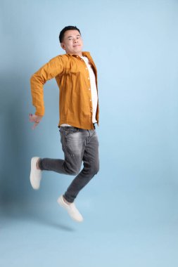The Asian LGBTQ man with yellow shirt standing on the blue background.