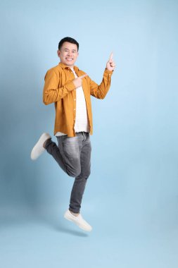 Mavi arka planda duran sarı gömlekli Asyalı LGBTQ adamı..