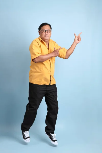 Adult Asian Man Yellow Shirt Jumping Blue Background — Stok fotoğraf