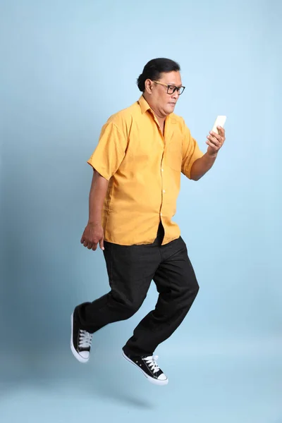 Adult Asian Man Yellow Shirt Jumping Blue Background — Fotografia de Stock