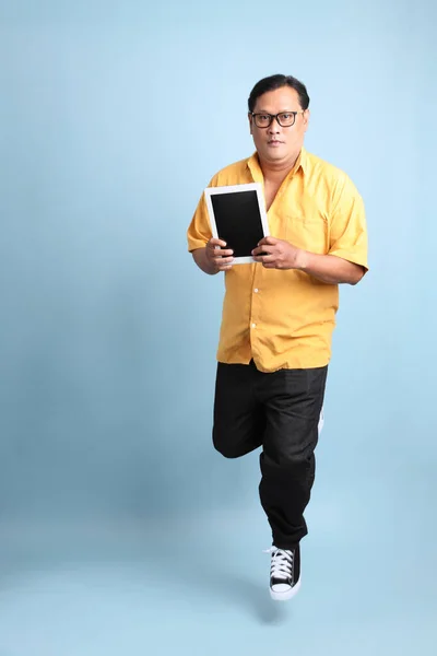 Adult Asian Man Yellow Shirt Jumping Blue Background — Stok fotoğraf