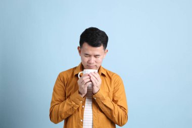 Mavi arka planda duran sarı gömlekli Asyalı LGBTQ adamı..