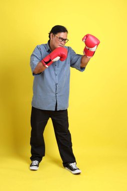 Sarı arka planda duran mavi gömlekli yetişkin Asyalı adam..