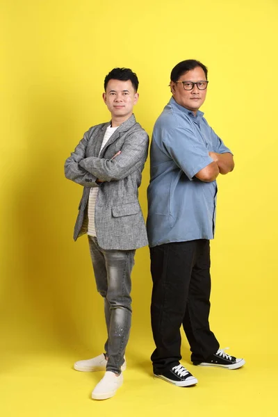 The adult two people standing on the yellow background.