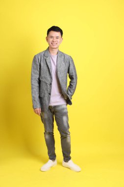Sarı arka planda gri ceketli Asyalı LGBTQ adamı..