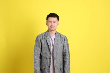 Sarı arka planda gri ceketli Asyalı LGBTQ adamı..