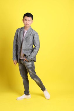 Sarı arka planda gri ceketli Asyalı LGBTQ adamı..