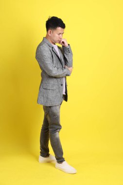 Sarı arka planda gri ceketli Asyalı LGBTQ adamı..