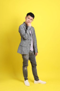 Sarı arka planda gri ceketli Asyalı LGBTQ adamı..