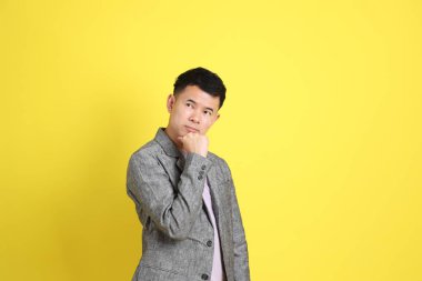Sarı arka planda gri ceketli Asyalı LGBTQ adamı..