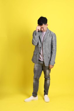 Sarı arka planda gri ceketli Asyalı LGBTQ adamı..