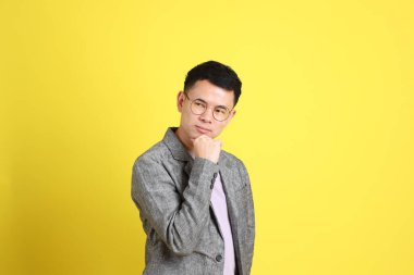 Sarı arka planda gri ceketli Asyalı LGBTQ adamı..