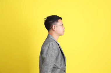 Sarı arka planda gri ceketli Asyalı LGBTQ adamı..