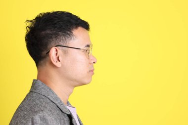 Sarı arka planda gri ceketli Asyalı LGBTQ adamı..